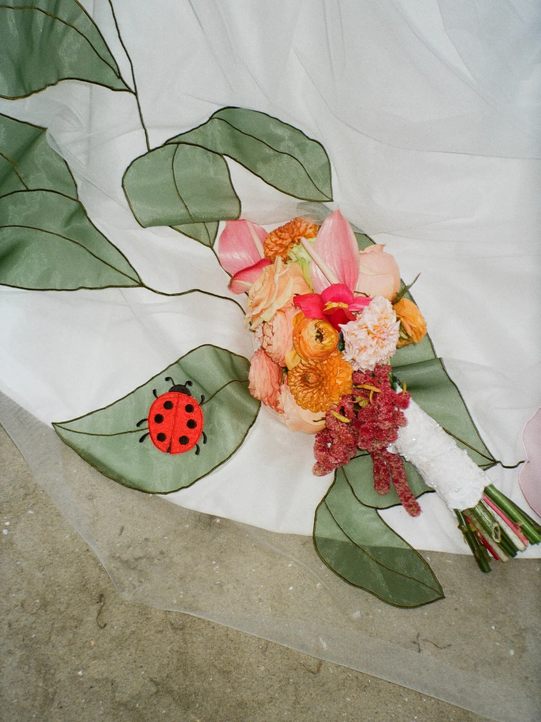 Real bride wearing a colorful Tara Bridal veil outdoors